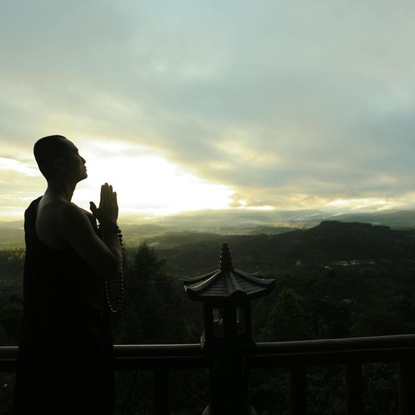 Silhouette of a man stretching at sunrise with a calm landscape.